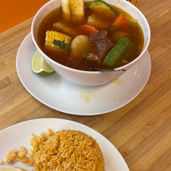 A hearty bowl of Mexican beef and vegetable soup with a side of orange rice.